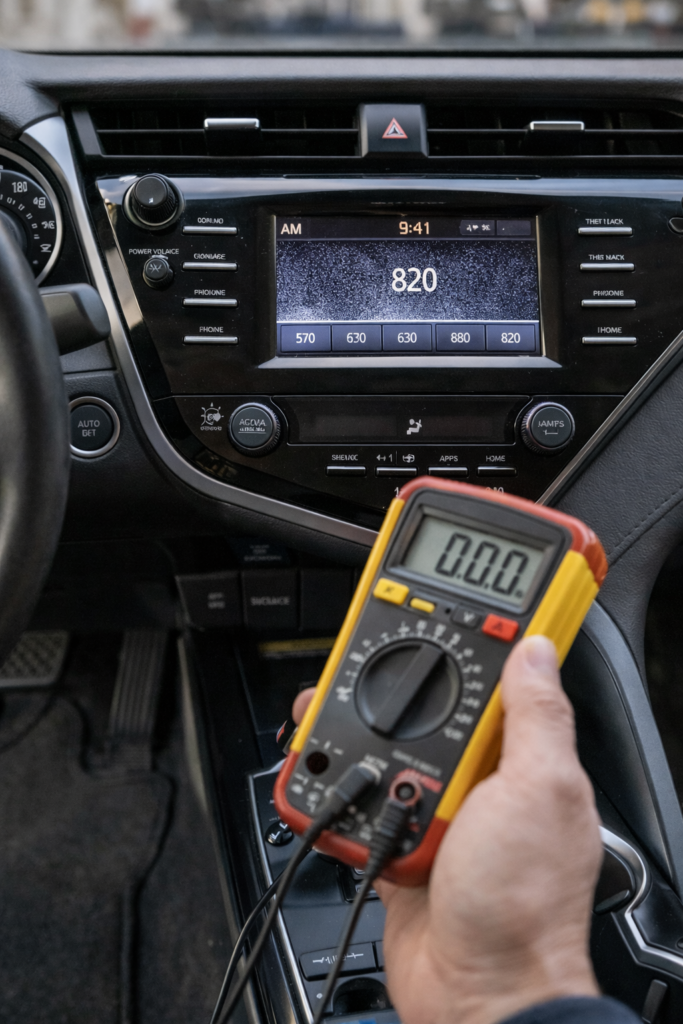AM radio troubleshooting in Toyota Camry with dashboard on static and multimeter testing power supply