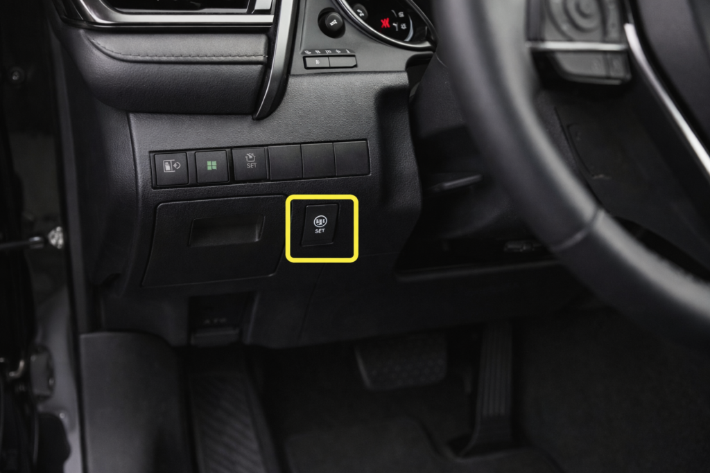 TPMS reset button under the dashboard near the steering column in a Toyota Camry, showing where to reset the TPMS light.
