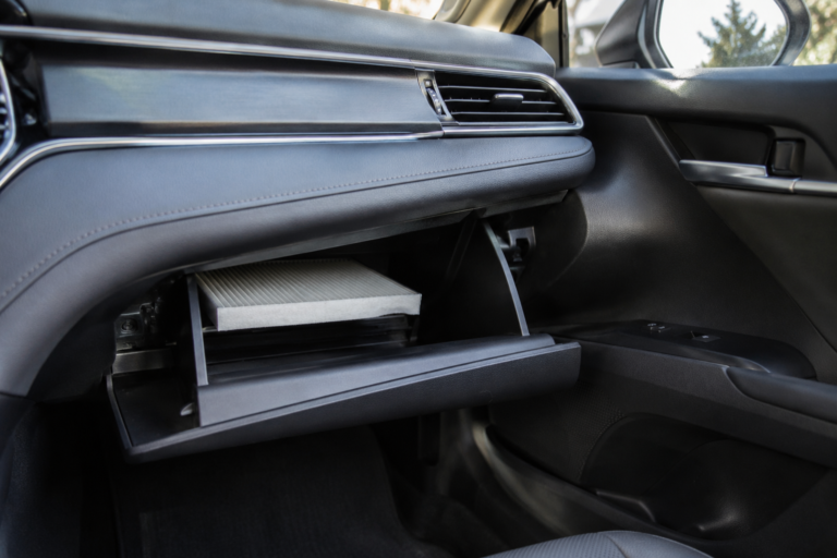 Toyota Camry cabin air filter location behind glove box during DIY replacement with clean automotive interior view