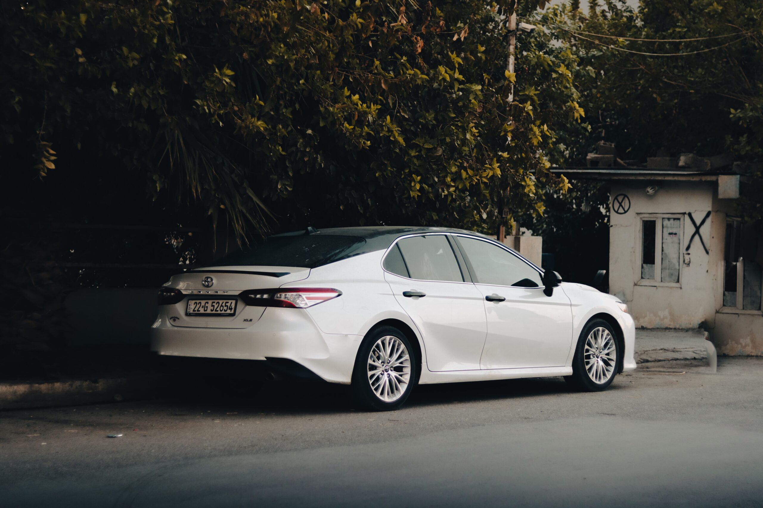 What Type of Car Is a Toyota Camry? White Toyota Camry midsize sedan parked roadside, showing its sleek design.